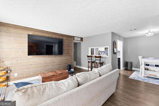 living room with wood walls, dark hardwood / wood-style flooring, and a textured ceiling