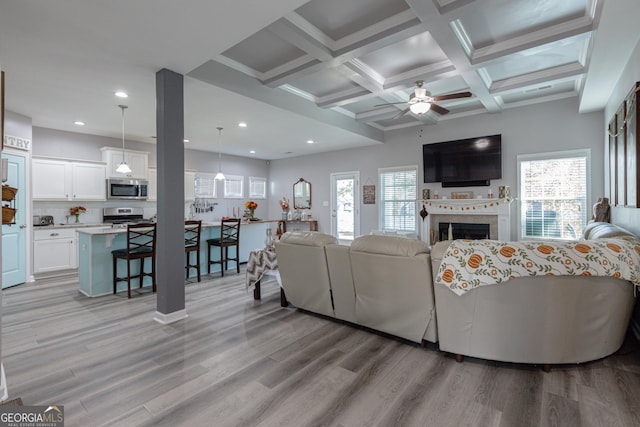 living room with beam ceiling, ceiling fan, light hardwood / wood-style flooring, and coffered ceiling