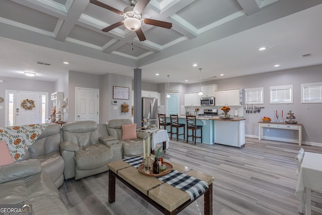 living room with coffered ceiling, ceiling fan, crown molding, beamed ceiling, and light hardwood / wood-style floors