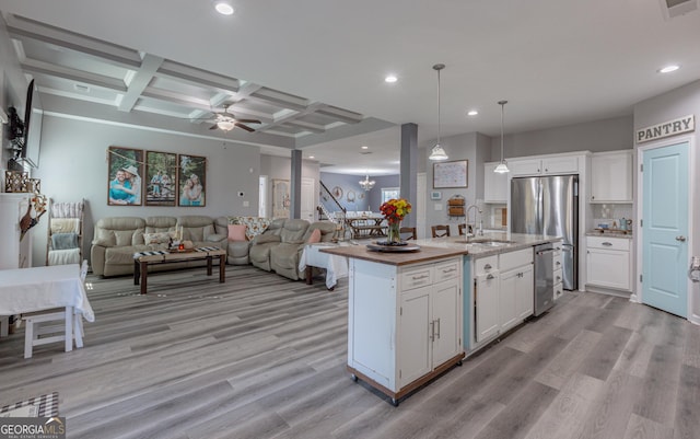 kitchen featuring white cabinets, sink, light hardwood / wood-style flooring, an island with sink, and decorative light fixtures