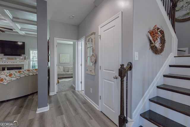 hall featuring beamed ceiling, light hardwood / wood-style floors, and coffered ceiling