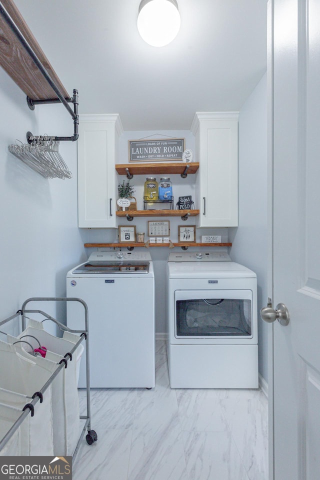 clothes washing area featuring washing machine and clothes dryer and cabinets