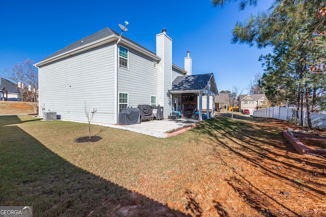 rear view of house featuring a lawn, cooling unit, and a patio