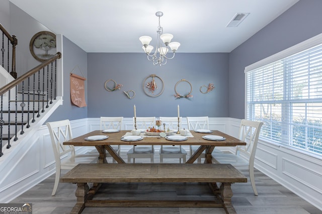 dining space with wood-type flooring, an inviting chandelier, and plenty of natural light