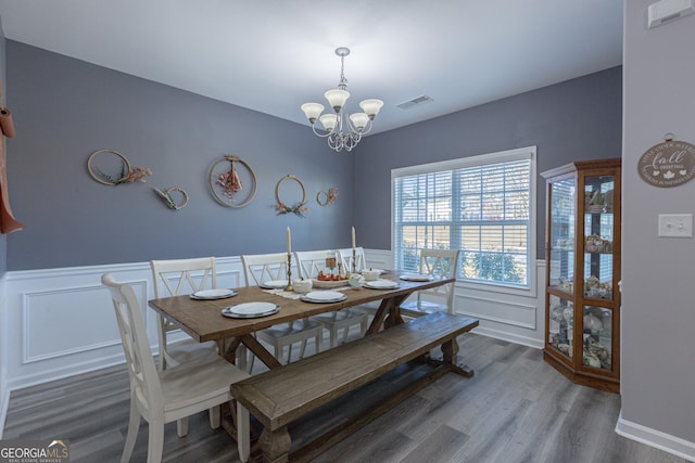 dining room with wood-type flooring and an inviting chandelier