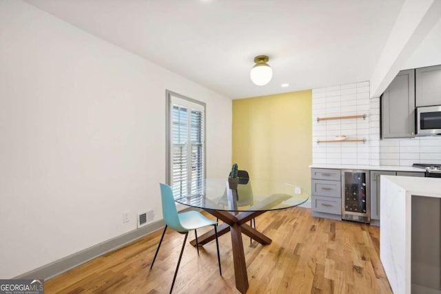 dining space with wine cooler and light hardwood / wood-style flooring