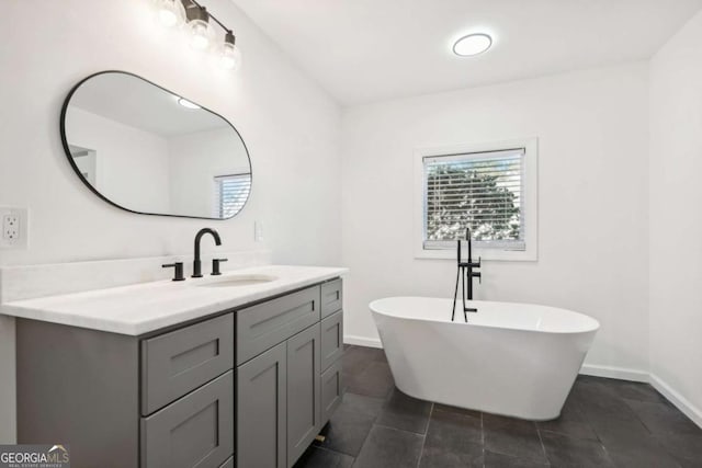 bathroom featuring tile patterned flooring, a bathing tub, a wealth of natural light, and vanity