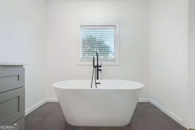 bathroom featuring vanity, a washtub, and tile patterned floors