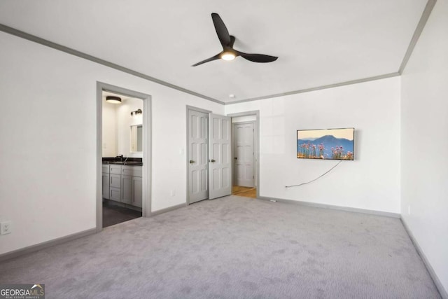 unfurnished bedroom featuring crown molding, carpet, sink, and ensuite bath