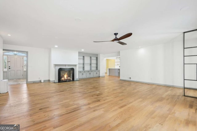 unfurnished living room featuring built in features, light hardwood / wood-style floors, and ceiling fan