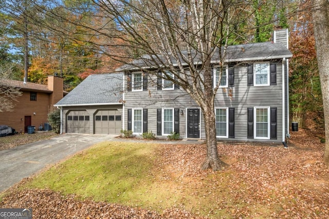 colonial-style house featuring central air condition unit and a garage