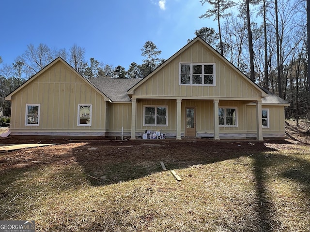 view of front of property with board and batten siding, covered porch, and roof with shingles