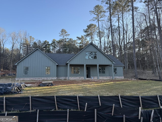 view of front of home with a shingled roof, board and batten siding, and a front yard