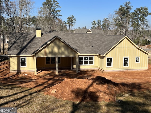 back of house featuring a shingled roof and a chimney