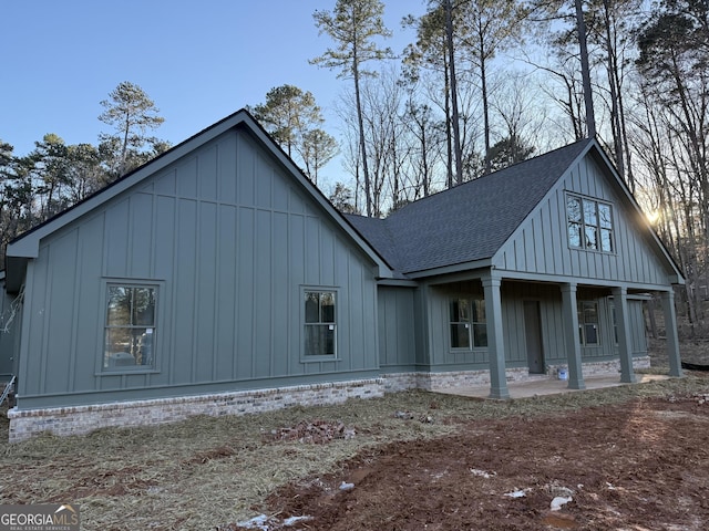 exterior space featuring a patio, a shingled roof, and board and batten siding