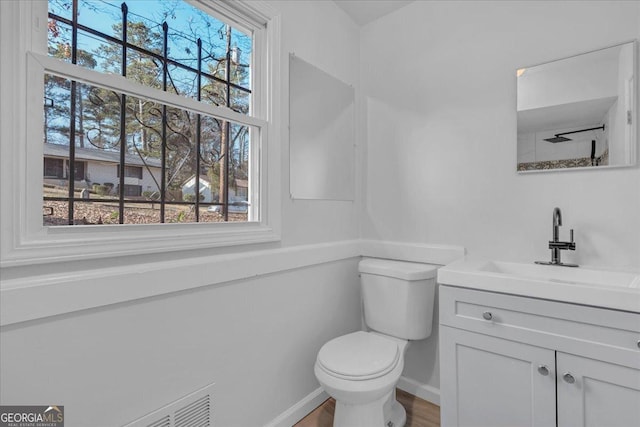 bathroom featuring a wealth of natural light, vanity, and toilet