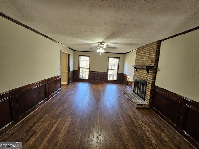 unfurnished living room featuring a fireplace, a textured ceiling, dark hardwood / wood-style floors, and ornamental molding