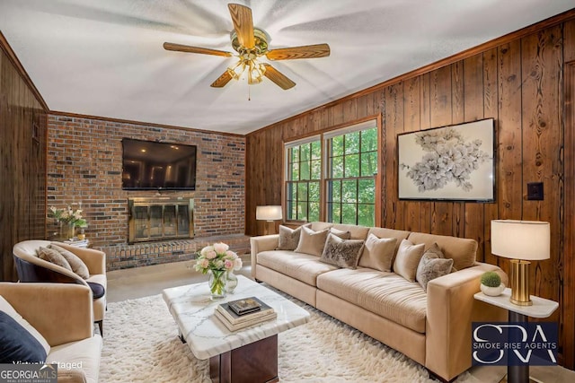 living room with a brick fireplace, wooden walls, ceiling fan, and ornamental molding