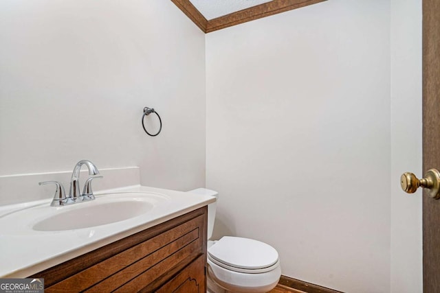 bathroom featuring toilet, vanity, and ornamental molding