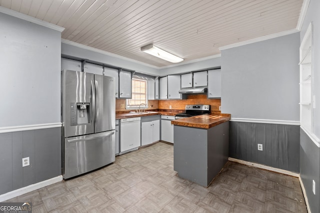 kitchen featuring butcher block countertops, crown molding, light parquet floors, wooden walls, and appliances with stainless steel finishes