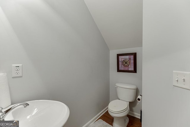 bathroom with toilet, sink, lofted ceiling, and hardwood / wood-style flooring