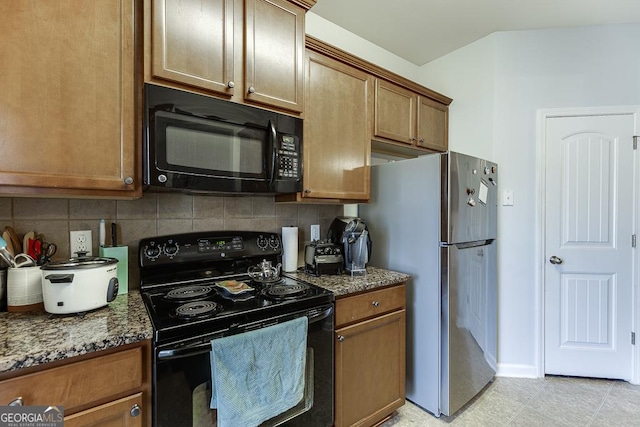 kitchen featuring black appliances, dark stone countertops, and tasteful backsplash