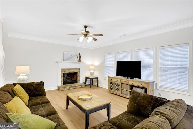 living room with a fireplace, light wood-type flooring, ceiling fan, and crown molding