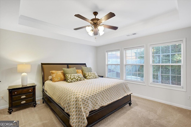 carpeted bedroom with a tray ceiling, ceiling fan, and crown molding