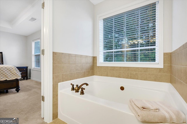 bathroom with plenty of natural light, a bathtub, and tile walls