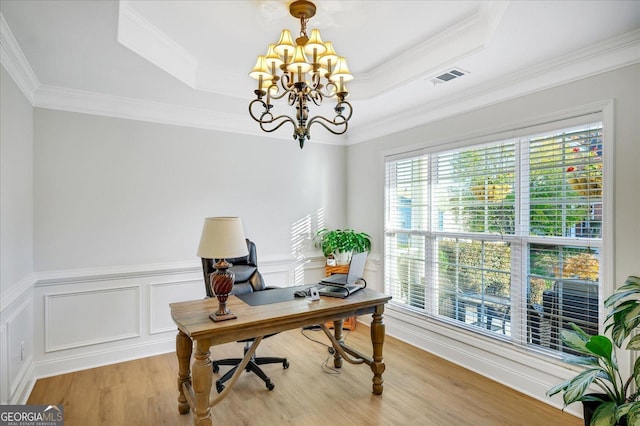 office space featuring a notable chandelier, crown molding, a tray ceiling, and light hardwood / wood-style flooring