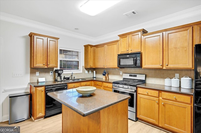 kitchen featuring a center island, light hardwood / wood-style floors, crown molding, and black appliances