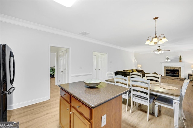 kitchen with a center island, ceiling fan with notable chandelier, black refrigerator, ornamental molding, and light hardwood / wood-style floors