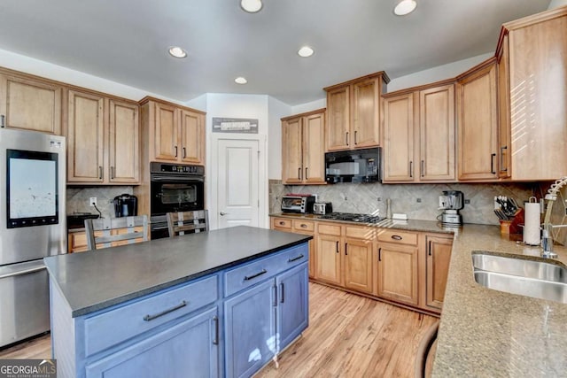 kitchen with a center island, black appliances, sink, tasteful backsplash, and light hardwood / wood-style floors