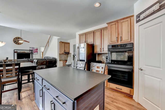 kitchen featuring a center island, double oven, stainless steel fridge, light hardwood / wood-style floors, and decorative backsplash