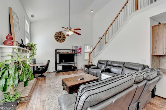 living room with ceiling fan, light wood-type flooring, and high vaulted ceiling