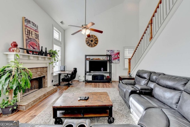 living room with a fireplace, hardwood / wood-style flooring, high vaulted ceiling, and ceiling fan