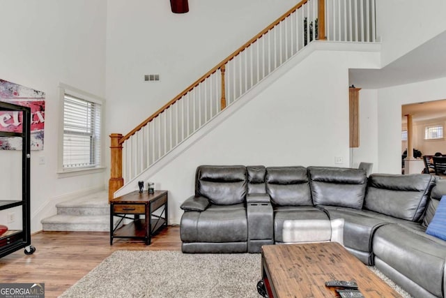 living room featuring a high ceiling, light hardwood / wood-style flooring, and ceiling fan