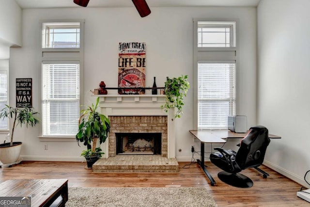 living area with hardwood / wood-style floors, a brick fireplace, and ceiling fan