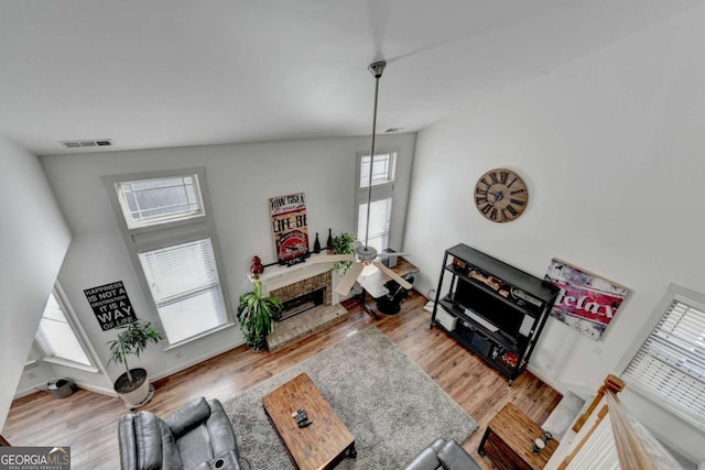 living room with a fireplace, high vaulted ceiling, and light wood-type flooring