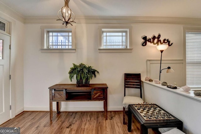 living area with a chandelier, crown molding, hardwood / wood-style floors, and a healthy amount of sunlight