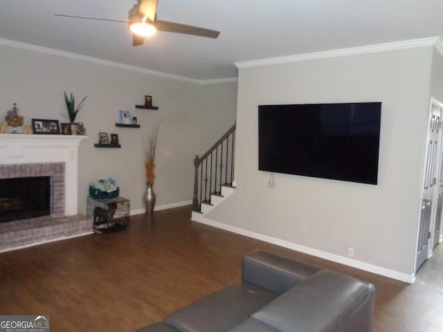 living room with ornamental molding, a brick fireplace, ceiling fan, and dark wood-type flooring