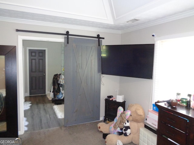 bedroom with a barn door, wood-type flooring, crown molding, and multiple windows