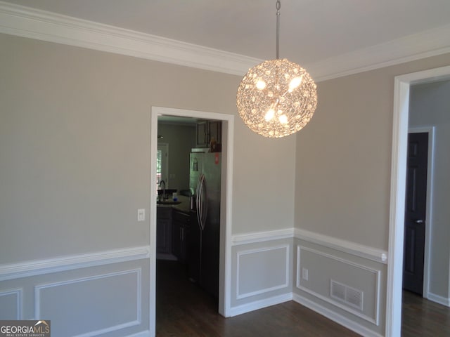 unfurnished dining area with dark hardwood / wood-style floors, ornamental molding, sink, and a chandelier