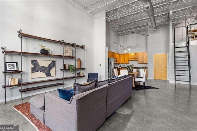 living room featuring a towering ceiling and concrete floors