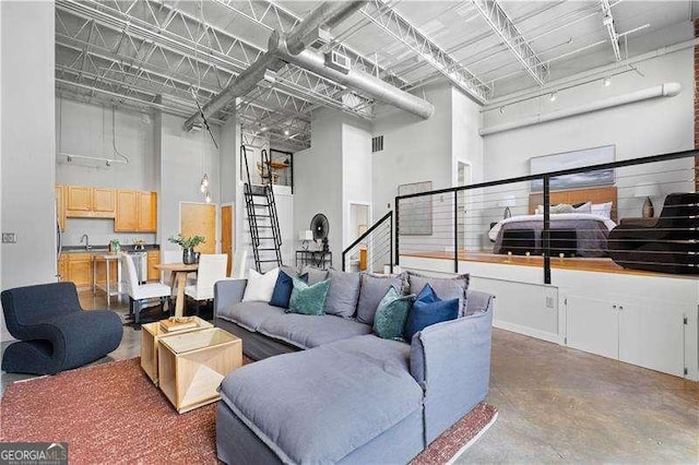 living room featuring sink, a towering ceiling, and concrete floors