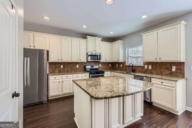 kitchen with a kitchen island, light stone counters, stainless steel appliances, and dark wood-type flooring