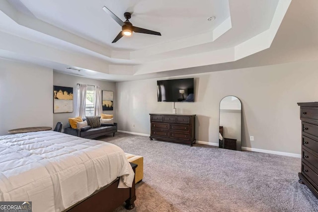 bedroom with a tray ceiling, ceiling fan, and light carpet