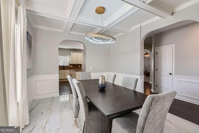 dining area with ornamental molding, light hardwood / wood-style flooring, coffered ceiling, and beam ceiling