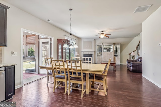 dining area featuring dark hardwood / wood-style flooring and ceiling fan with notable chandelier