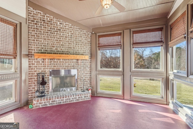 unfurnished living room featuring ceiling fan, a healthy amount of sunlight, and a brick fireplace